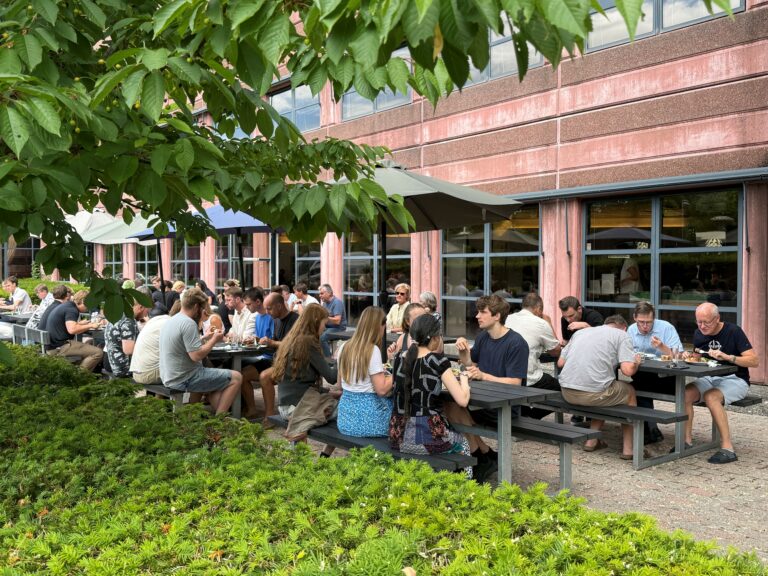 Mennesker spiser frokost ved udendørs borde